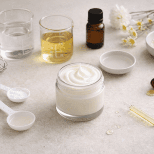 Pot de crème hydratante naturelle entouré d’ingrédients cosmétiques bruts (eau, huile végétale, glycérine, vitamine E) disposés sur un plan de travail clair, illustrant un atelier cosmétique DIY.