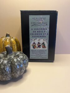 Vue d’ensemble du kit – Les 6 sorcières en bois brut, mini set de peintures et pinceau disposés dans leur boîte kraft.